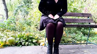 Peeing with legs spread wide on a bench in an autumn park