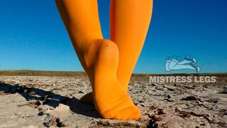 Barefoot walking by dried up lake in yellow pantyhose